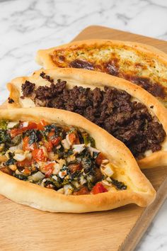 two meat and vegetable empanadas on a cutting board