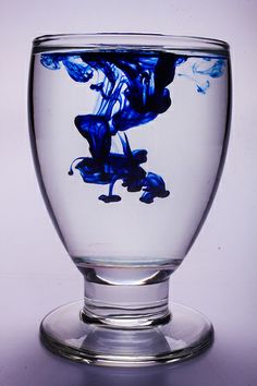 a glass filled with blue liquid sitting on top of a table