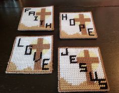 four cross stitch coasters sitting on top of a table