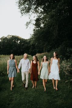 a group of people holding hands and walking in the grass