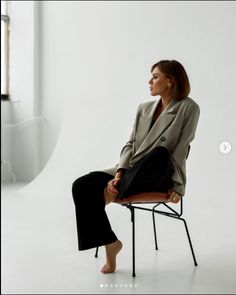 a woman sitting in a chair with her legs crossed and looking off to the side