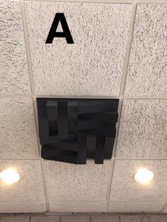 a black piece of paper hanging on the side of a wall next to two lights