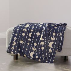 a blanket with stars and moon on it sitting on top of a couch in front of a white wall