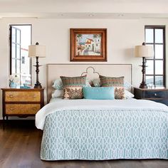 a large bed sitting next to two lamps on top of a hard wood floored bedroom