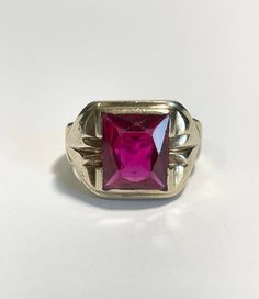 Handsome vintage 10k yellow gold 1940s era ring featuring a vibrant created ruby! The deep red gem weighs an estimated 8.48 carats, is Emerald cut, and bezel set. The substantial setting is detailed with decorative designs on the shoulders. Charming vintage piece of fine jewelry for him or her, featuring July's birthstone!  ERA - Circa 1940s, Retro Era METAL / MATERIAL - 10k yellow gold, 1 created ruby (estimated 8.48 carats) [Synthetic ruby contains essentially the same chemical composition & p Classic Ruby Ring With Polished Finish For Collectors, Classic Red Signet Ring Stamped 14k, Vintage 14k Gold Signet Ring With Center Stone, Collectible Red Ruby Ring In 14k Gold, Vintage Ruby Rings With Polished Finish, Antique Ruby Rings With Polished Finish, Vintage Red Hallmarked Signet Ring, Antique Red 14k Gold Signet Ring, Antique Ruby Signet Ring