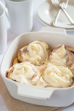 a white dish filled with cinnamon rolls on top of a table