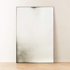 a white square mirror sitting on top of a wooden floor next to a black and white wall