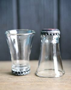 two clear glass vases sitting on top of a wooden table next to each other