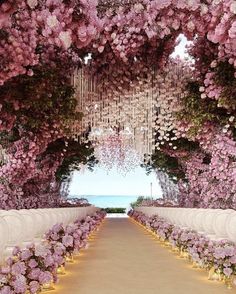 the aisle is lined with rows of flowers and chandeliers hanging from the ceiling