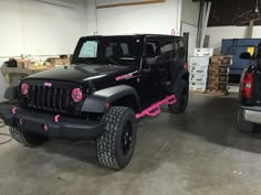 a black jeep with pink decals parked in a garage