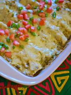 a casserole dish with meat, vegetables and cheese in it sitting on a colorful table cloth