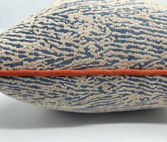 a blue and white pillow with an orange line on it