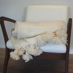 a chair with a blanket on top of it and two pom - poms hanging from the back