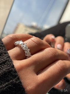 a woman is holding her engagement ring in her hand