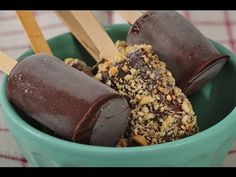 three chocolate covered pops in a green cup