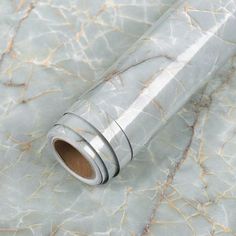 a roll of silver foil sitting on top of a marble tablecloth covered in cracks