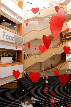 red hearts are floating in the air above an escalator at a shopping center