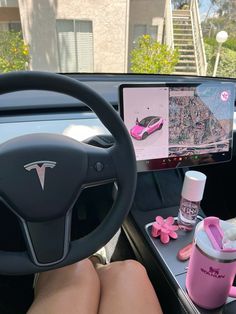 a woman is sitting in the driver's seat of a car with pink accessories