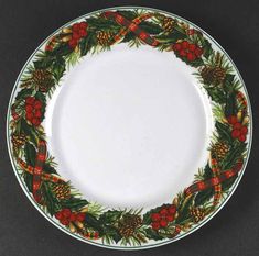 a christmas wreath plate with pine cones and holly berries on the rim, decorated with red ribbon