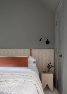 a white bed sitting next to a door in a bedroom