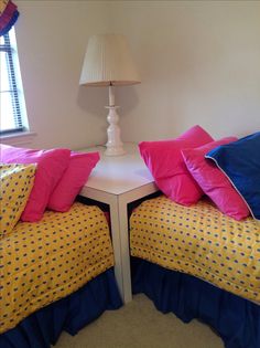 two twin beds with yellow and blue bedding in a bedroom next to a window