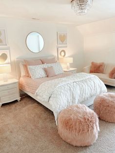 a bedroom with white furniture and pink pillows on the bed, along with round mirrors