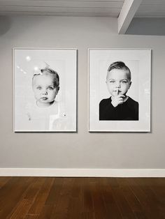 two black and white photos hanging on the wall next to each other in an empty room