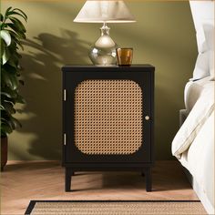 a black cabinet with wicker doors and a lamp next to it on a wooden floor