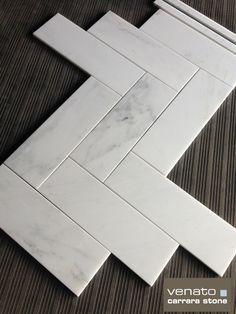 the white marble tile is laying on top of the wooden floor and has an interesting pattern