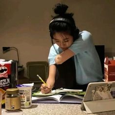 a woman sitting at a table writing on a book