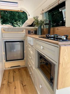 an rv kitchen with wood flooring and built in ovens, cabinets and drawers