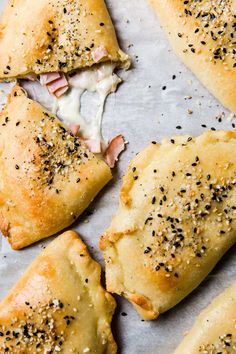 several pieces of pizza with cheese and black pepper sprinkled on them sitting on a piece of parchment paper