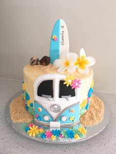 a cake decorated with flowers and surfboards on top of a glass platter in the shape of a vw bus