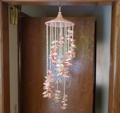 a wooden door with a light fixture hanging from it's side and flowers on the front