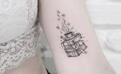 a woman's arm with a tattoo on it that has a stack of books