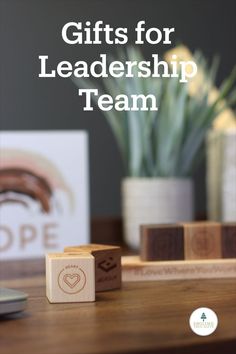 wooden blocks with the words gifts for leadership team on them and a potted plant