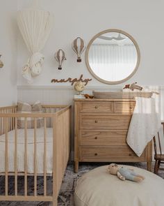 a baby's room with a crib, dresser and mirror