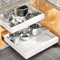 pots and pans are stored in the bottom drawer of a kitchen cabinet that is open