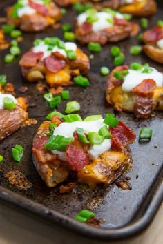 bacon, cheese and green onions are on top of the baked potato skins that have been topped with sour cream