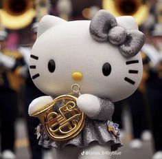 a hello kitty figurine holding a french horn in front of a marching band