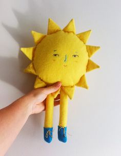 a hand holding up a yellow stuffed sun