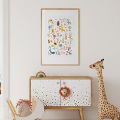 a baby's room with a giraffe toy next to a white dresser