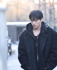 a young man standing on the street with his hands in his pockets