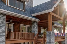 the front porch of a house with stone pillars and wood railings on both sides