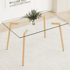 a glass table sitting on top of a white carpeted floor next to a plant