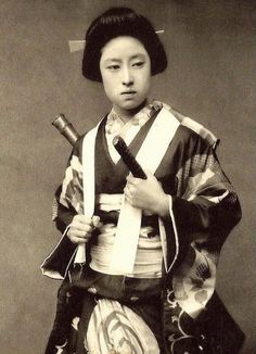 an old black and white photo of a woman in kimono holding two japanese swords