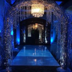 the entrance to a wedding venue decorated with blue lights and chandelier hanging from the ceiling