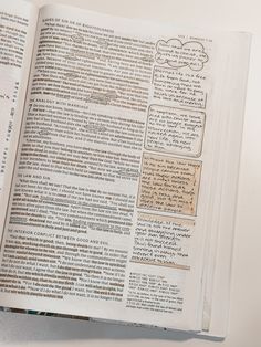 an open book with writing on it sitting on top of a white table next to a cell phone