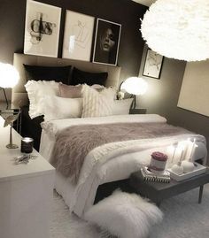 a white bed sitting in a bedroom next to two lamps and pictures on the wall