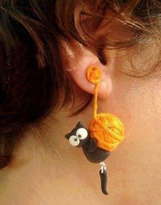 a close up of a person's ear with an orange yarn ball attached to it